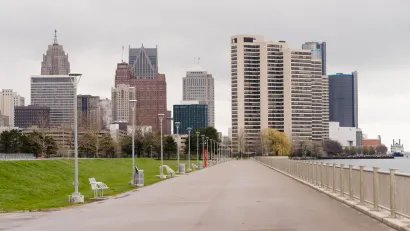 Waterfront walkway with benches and Detroit skyline in the background